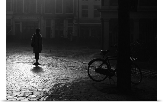 A silhouetted woman standing in a street near a bicycle, Haarlem, Netherlands.