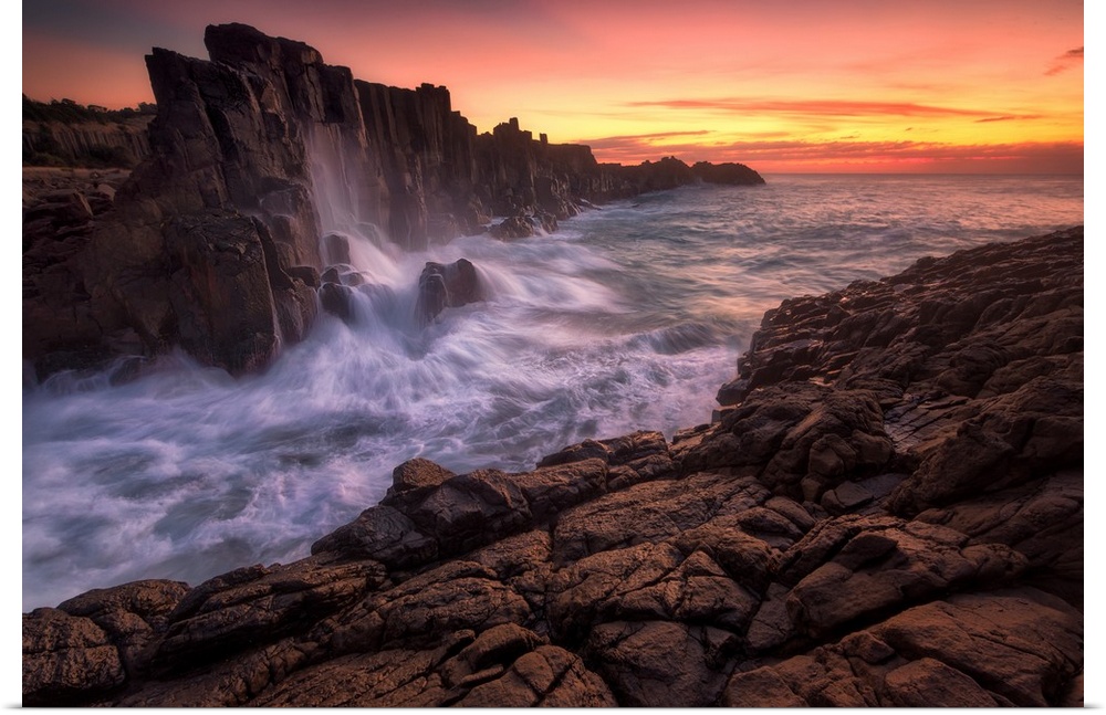 Long exposure landscape photograph of rock formations with rushing water at sunrise, Kiama, Australia.