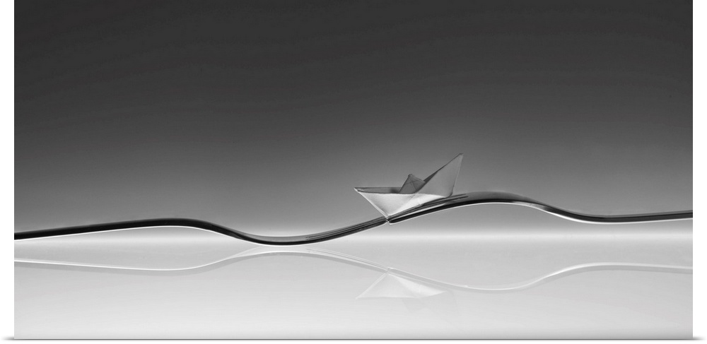 A small folded paper boat resting on two forks resembling a wave.