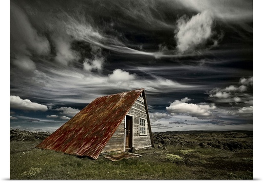 An abandoned shack in Iceland under a blanket of wispy clouds.