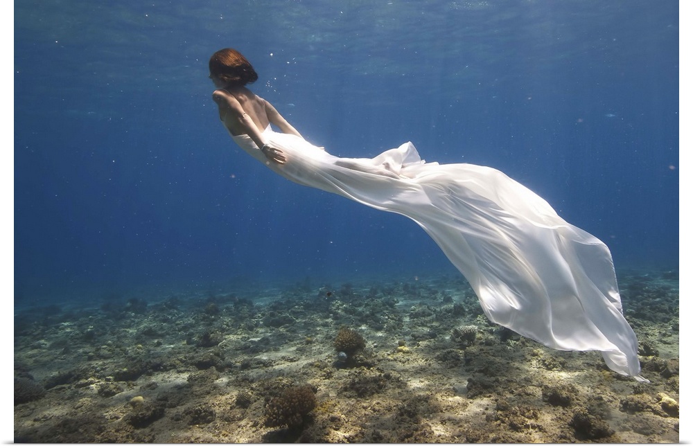 Woman in a flowing white dress swimming underwater.