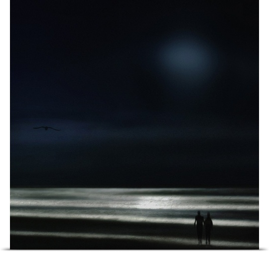 A silhouetted couple walking along a beach at night.