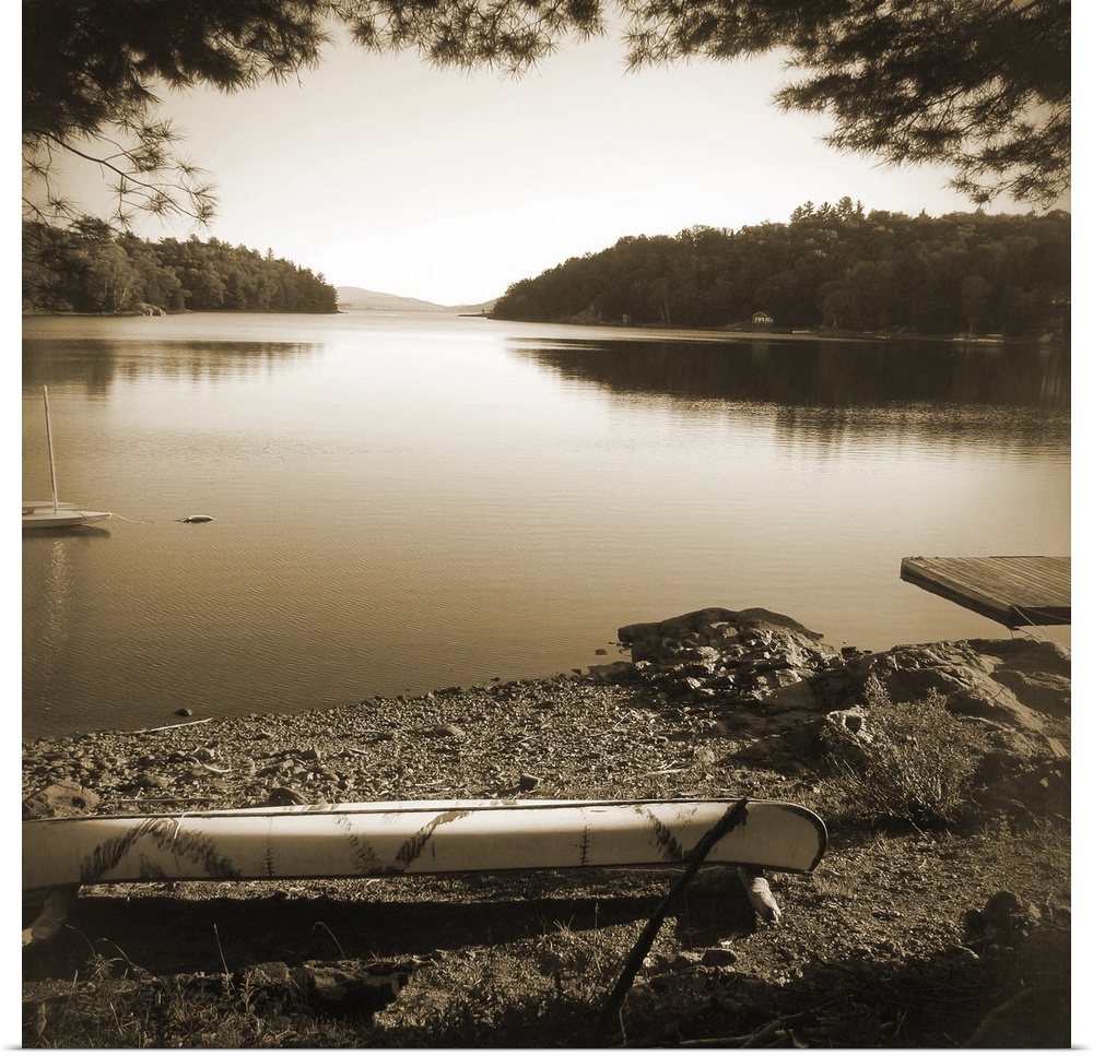 Sepia toned photograph of a canoe resting on the shores of a lake in an idyllic wilderness scene.