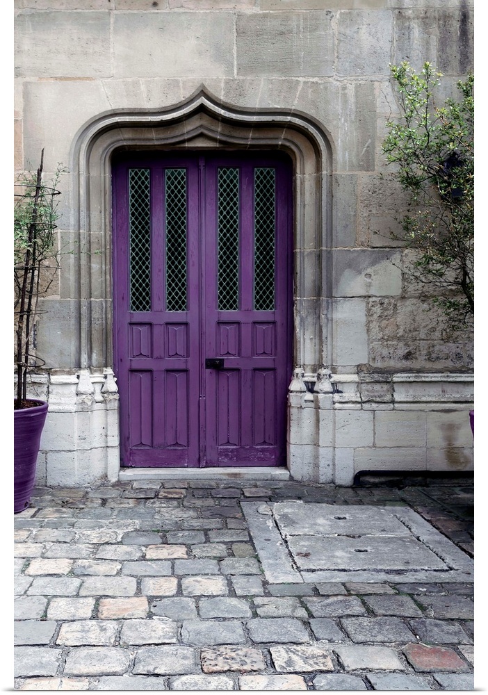 Fine art photograph of a purple door in a stone wall on a cobblestone street.
