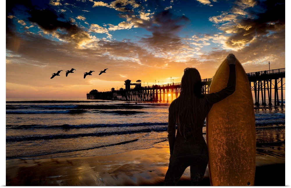 A female surfer watches the last waves near the Oceanside Pier, Oceanside, California, USA