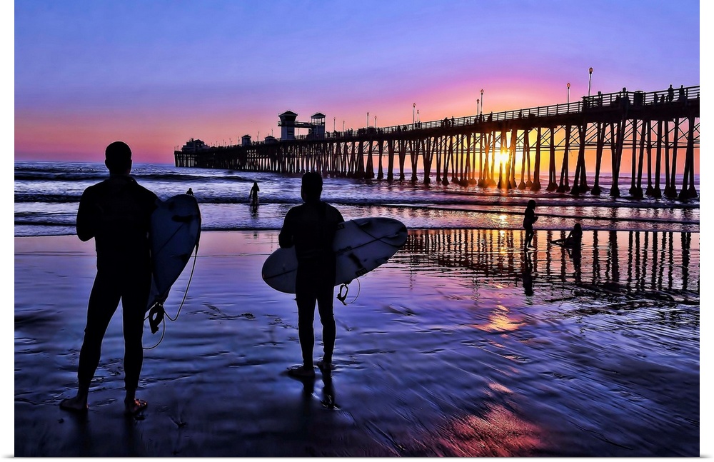 Surfers at sunset near the iconic Oceanside Pier. Oceanside is 35 miles North of San Diego, California, USA.