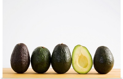 A Row Of Avocados With Interior Of One Showing Standing Upright