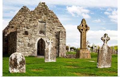 Ancient stone roofless church with celtic crosses in a grassy field, Ireland