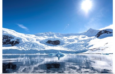 Bright sun and snow on the mountains reflected in the water of Neko Harbor, Antarctica