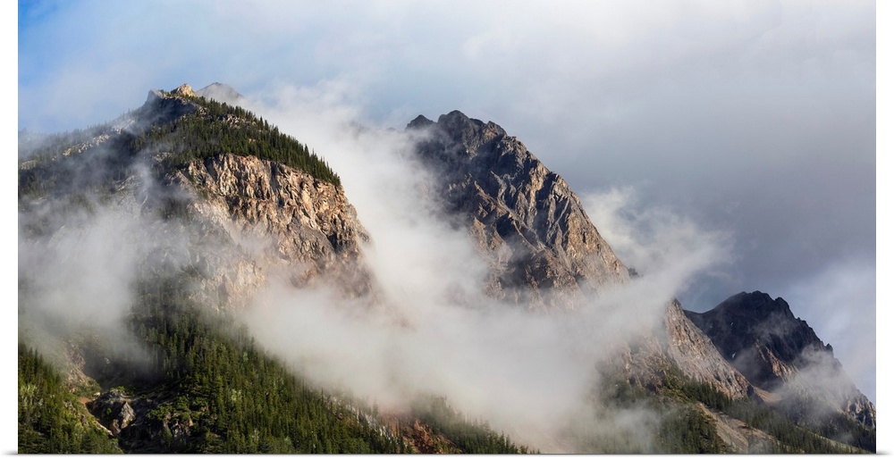 Clouds gather around rocky mountain peaks, field, British Columbia, Canada.