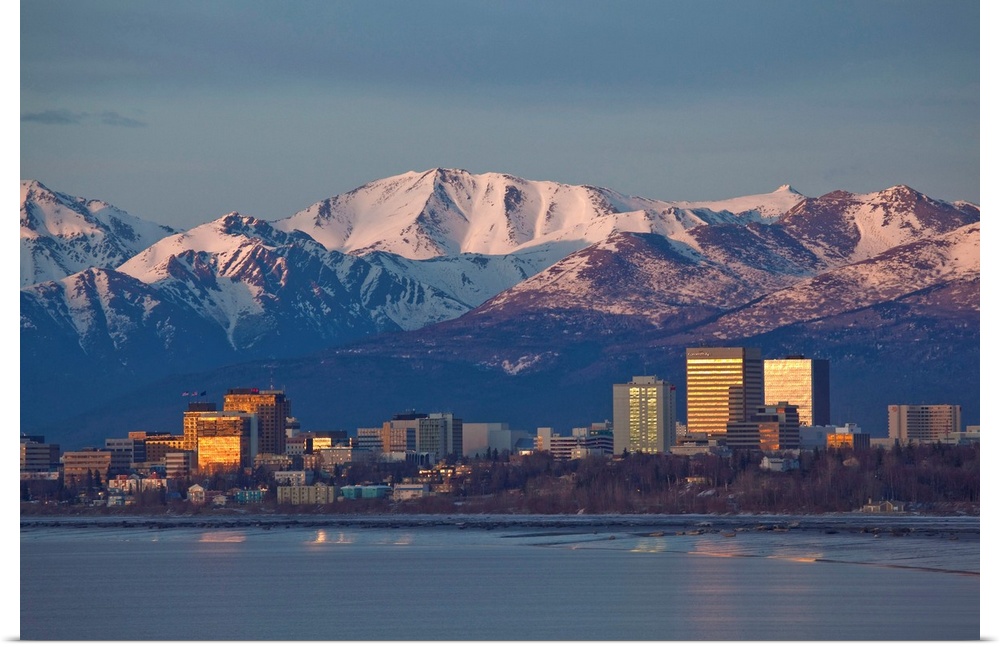 Chugach mountain range seen behind a wide angle view of downtown Anchorage with mudflats in the foreground.
