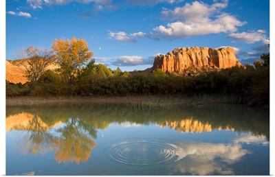 Fall color and rock formations casting reflections in calm water.