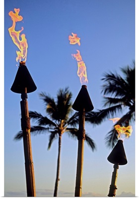 Hawaii, Tiki Torches Lit At Dusk, Palm Trees And Blue Sky