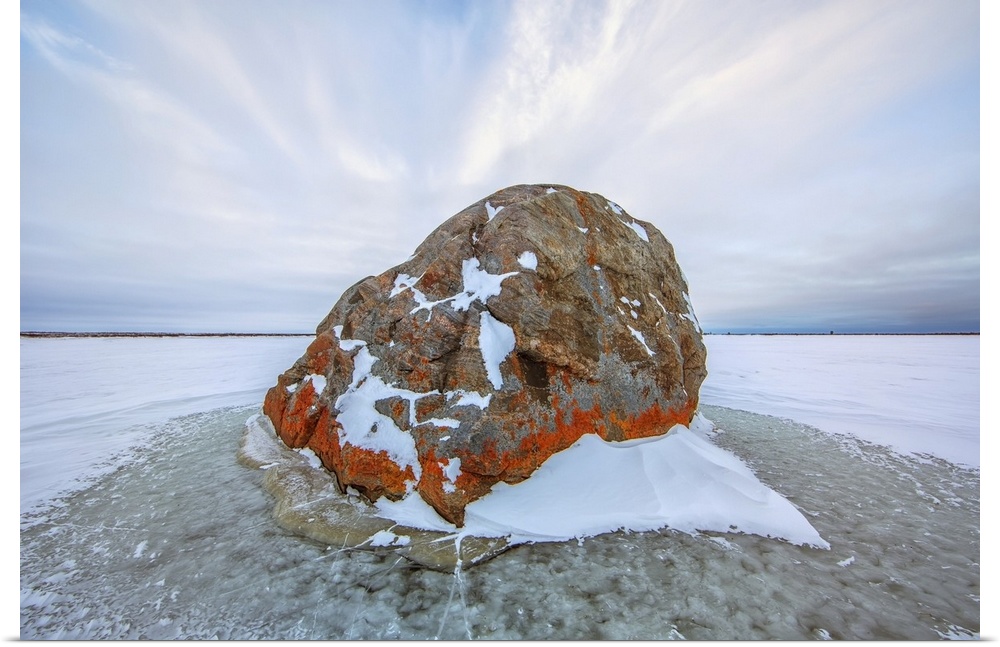 Large lichen covered rock in a frozen lake situated on the flats beside hudson's bay, Manitoba, Canada
