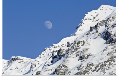 Moon rising over snow covered mountain peak at Hatcher Pass in Southcentral Alaska