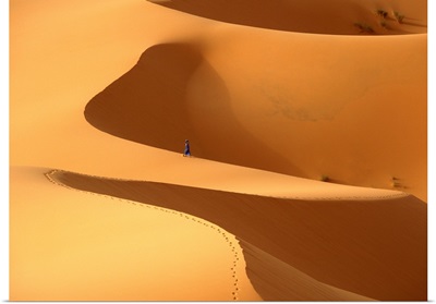 Morocco, Berber 'blue man' walking through sand dunes in Erg Chebbi area, Sahara Desert