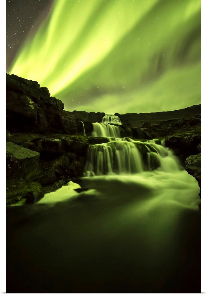 Northern Lights, or Aurora Borealis, glowing over waterfalls and a stream; Iceland