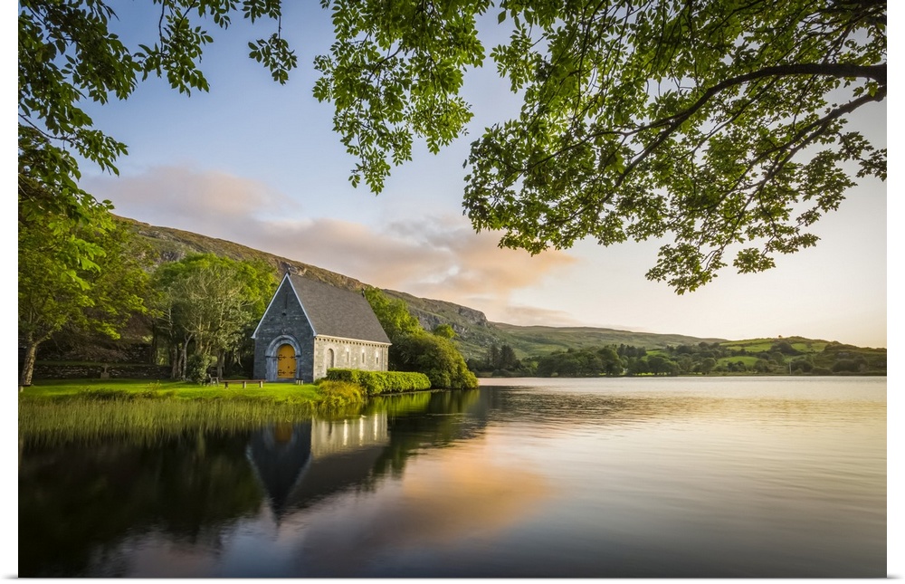 Old chapel of Gougane Barra situated by a lake and framed by green trees at sunrise; Gougane Barra, County Cork, Ireland.