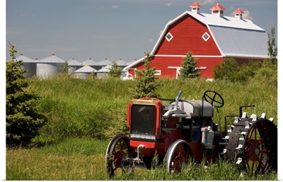 Old Red Tractor In A Field With A Red Barn In The Background, Alberta, Canada