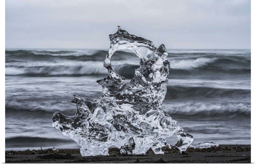 Piece of ice on diamond beach, near Jokusarlon, with the ocean behind it along the south coast of Iceland, Iceland.