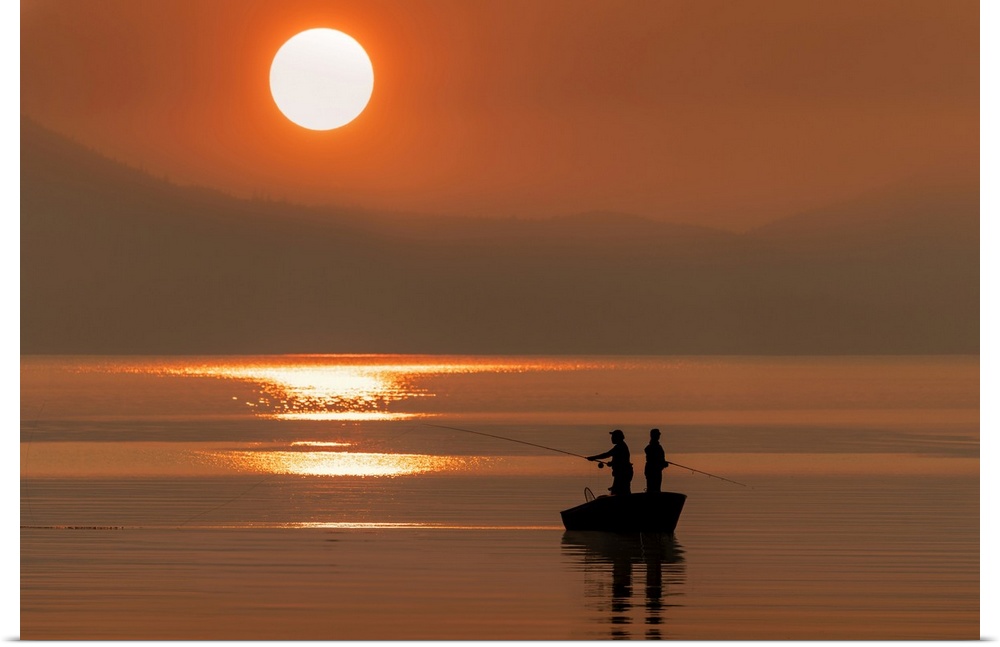 Silhouetted anglers standing in a boat fishing for salmon at sunset; Juneau, Alaska, United States of America