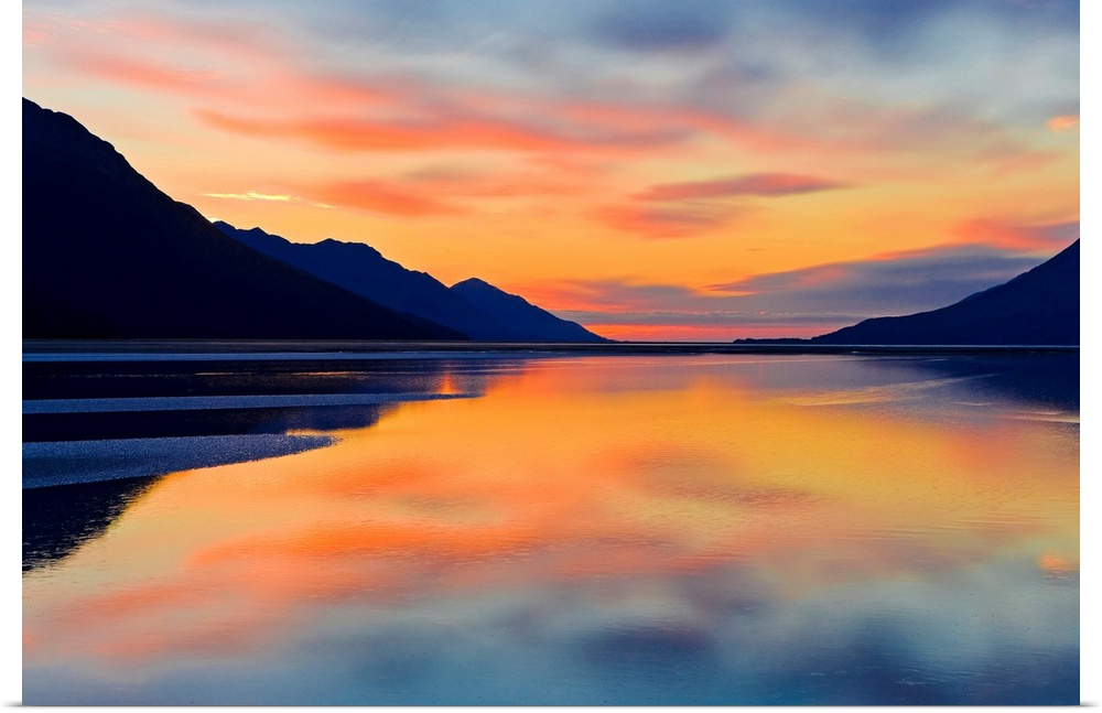 Expansive photograph of the Turnagain Arm in the Cook Inlet in Alaska (AK) during sunset. Calm water is bordered on both s...