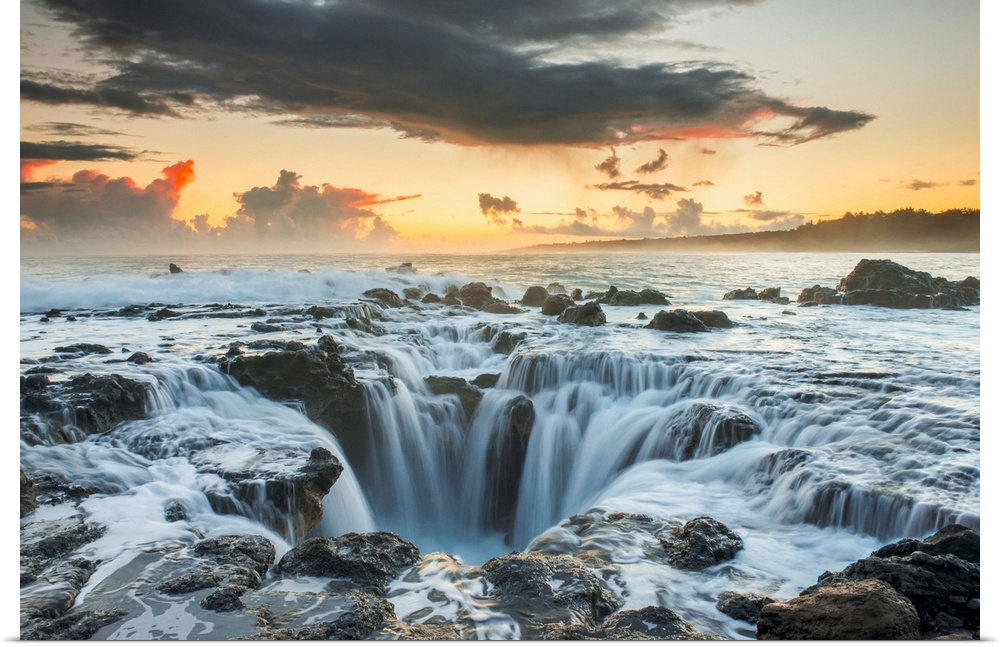 Surf spills into a hole in a rock outcrop on the east side of Kauai. Kauai, Hawaii, United States of America.