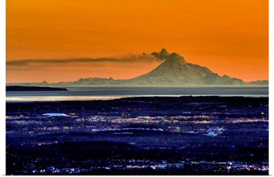 The city of Anchorage Alaska at sunset with Mount Redoubt erupting in the background