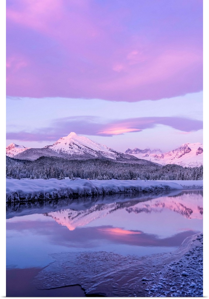 Alpenglow colours the snow-covered coastal range mountains, Mendenhall Glacier and Mendenhall towers are reflected in the ...