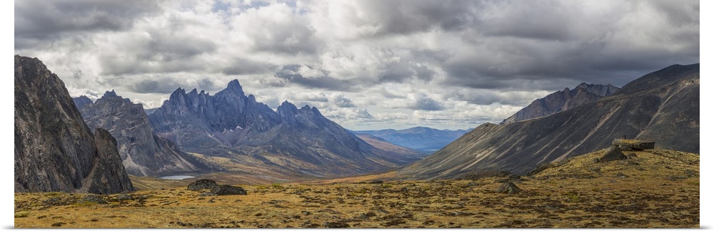 Men standing on a boulder in the distance in Tombstone Territorial Park in autumn. Yukon, Canada.