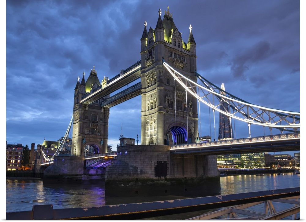 Tower Bridge illuminated at dusk and reflected in the tranquil water of the River Thames; London, England.