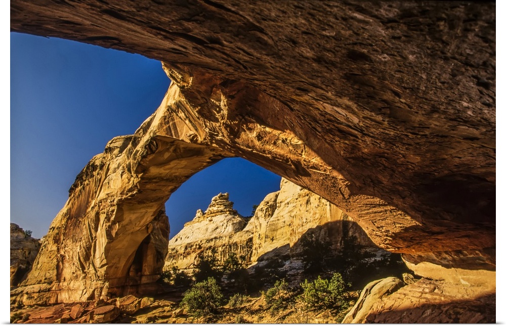 Underneath the Hickman Natural Bridge looking through the arch at the sandstone cliffs in the Capitol Reef National Park U...