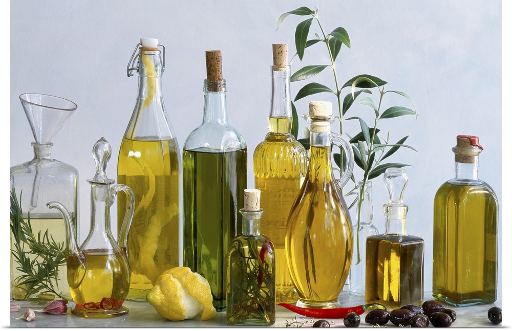 Various types of olive oils in bottles with herbs, lemon and olives