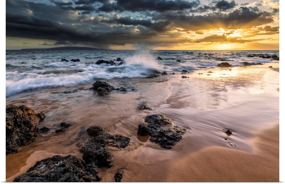 Water splashing on the beach with a golden sunset over the ocean; Hawaii, United States of America
