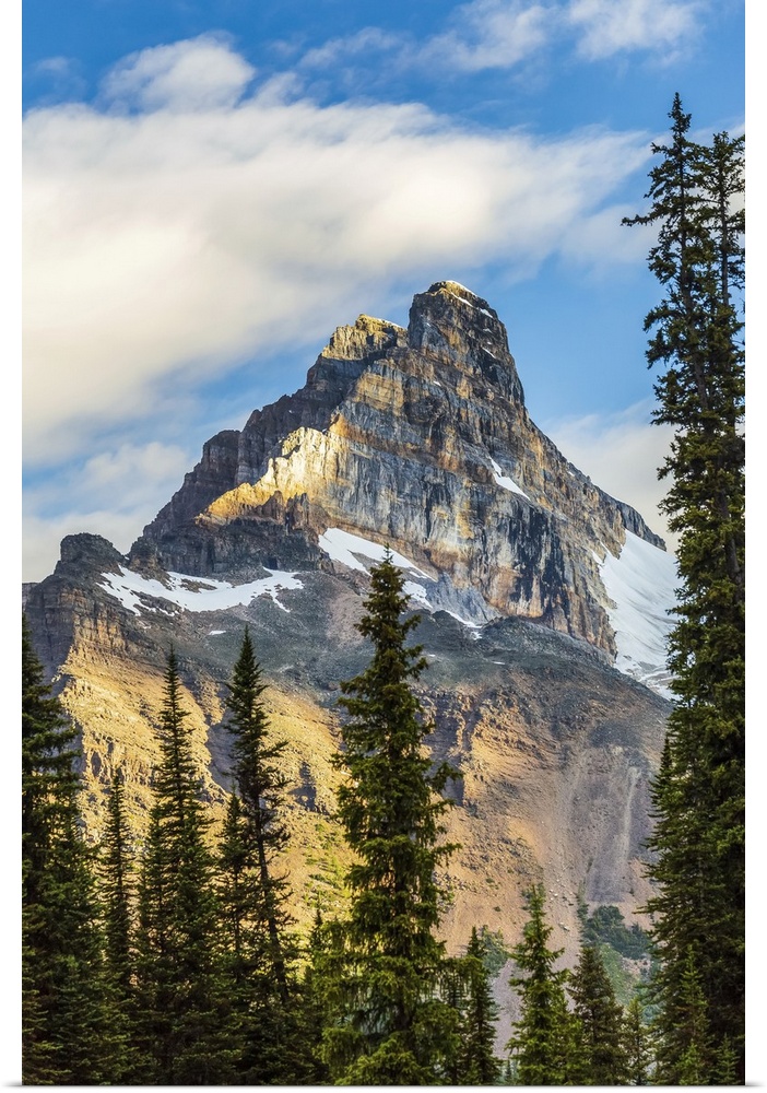 Mountain cliff peak dramatically lit by the sun with blue sky and clouds, Yoho National Park; Field, British Columbia, Canada
