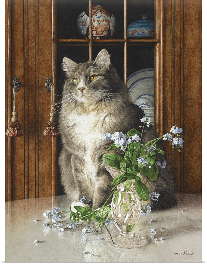 Vertical image of a white and gray cat sitting on a table next to a glass vase of blue flowers.
