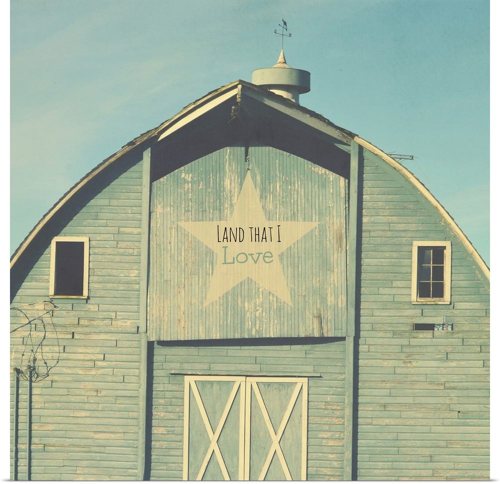 Square photograph of a blue tinted barn with a star sign that reads "Land That I Love" on the top.