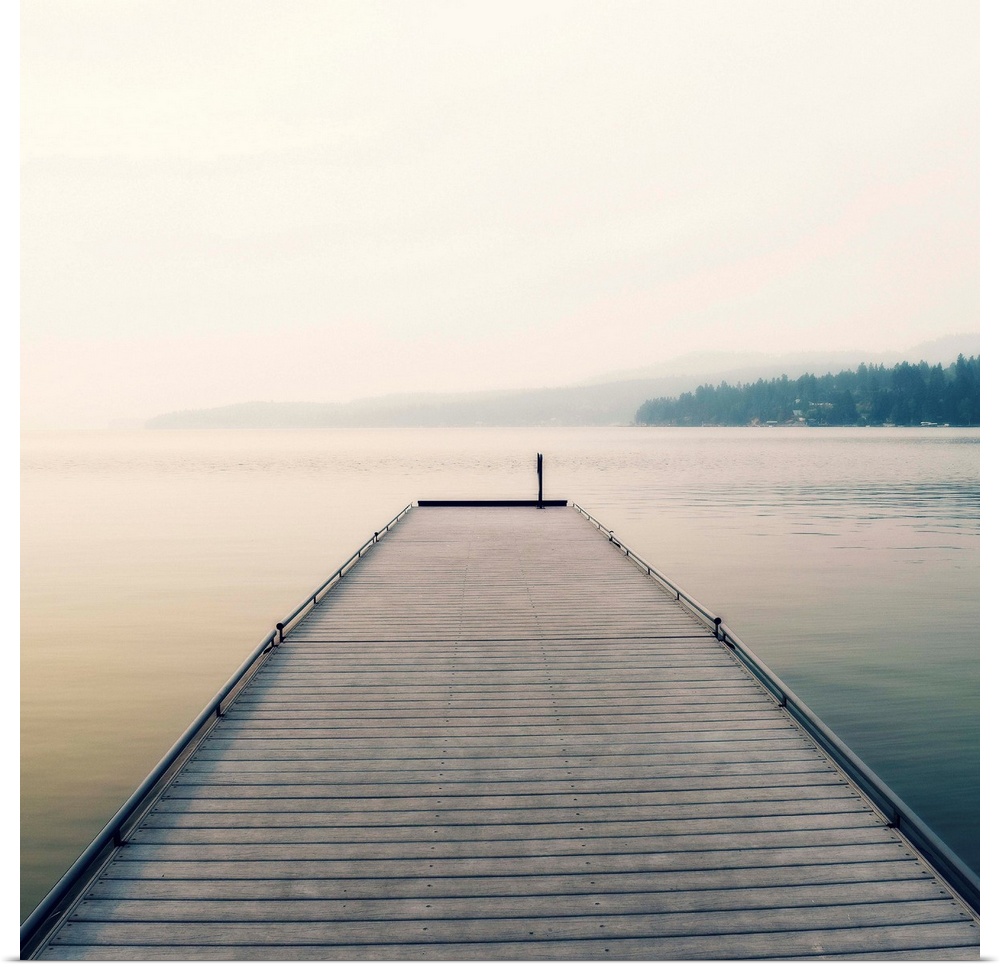 Square photograph of a wooden pier leading out the the middle of a foggy lake.