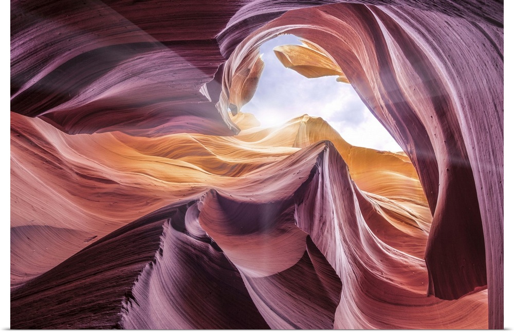 An artistic photograph looking up at the opening of Antelope canyon with sunlight shining in.