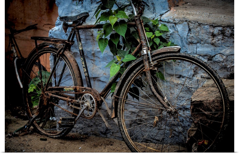 Photograph of an old bicycle parked next to a bright blue wall.
