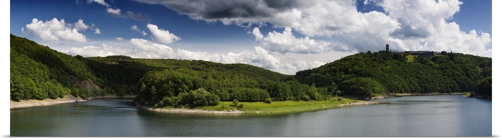 Panoramic photograph of a lake in the Eifel range in Germany under cloudy skies.