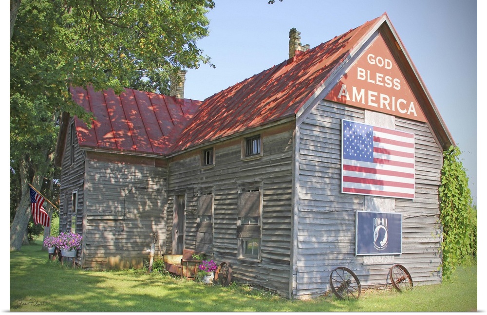 A photograph of a rustic country home with an American flag on the side.
