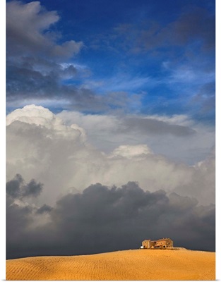 Golden wheat field, house and storm clouds