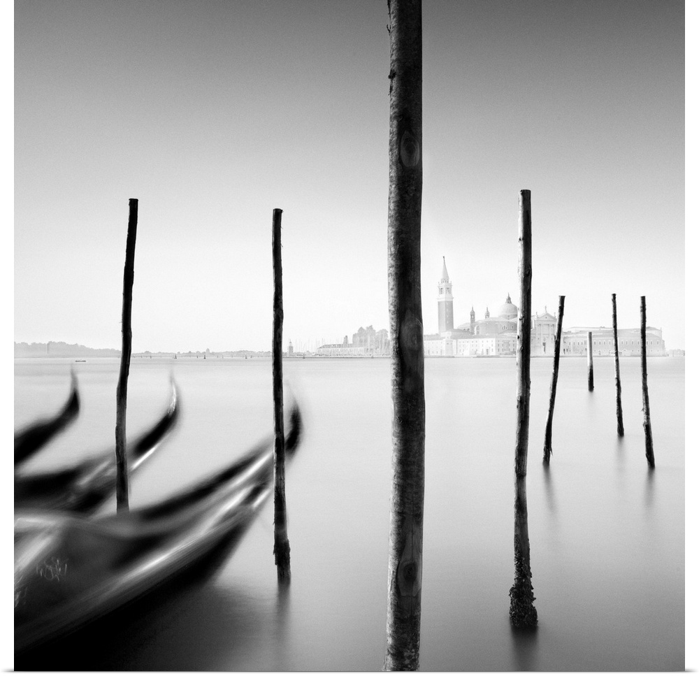 An artistic black and white photograph of gondola docked at harbor in Venice.