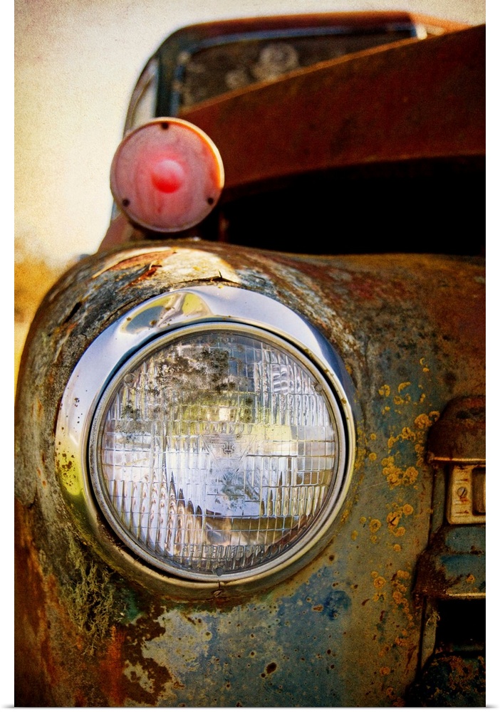 Photograph of a headlight of on the front of a vintage car.