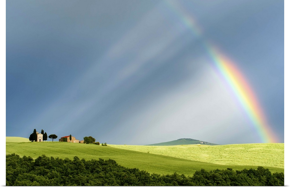 A photograph of a Tuscan countryside bathed in the light streaming from a rainbow.