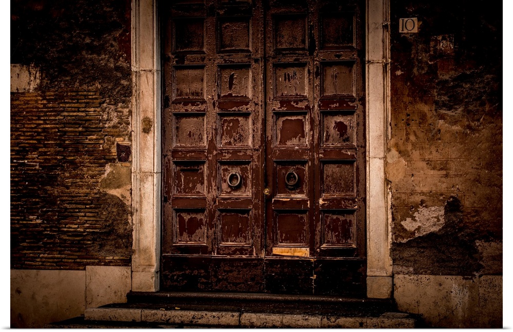 Photograph of large, old, wooden front doors on a run down facade.