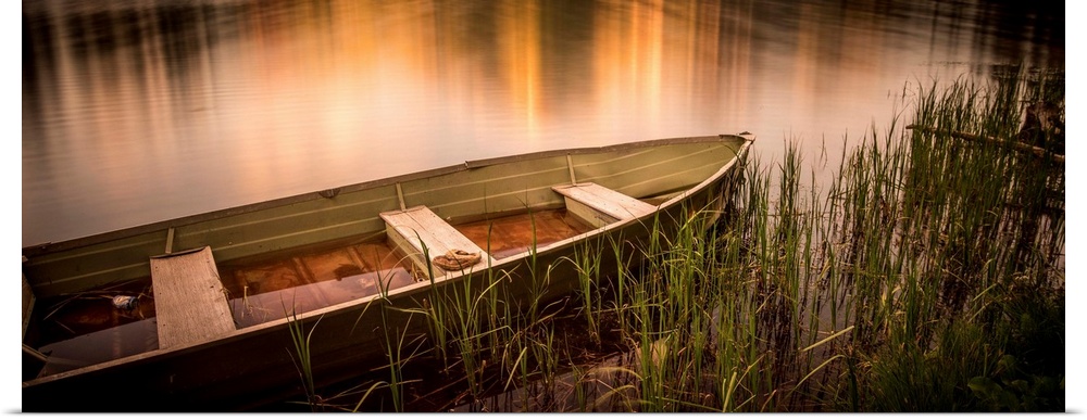 A photograph of a rowboat siting still in the water.