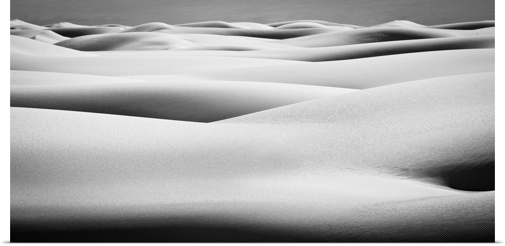 Black and white landscape photograph of contrasting hilly sand dunes.