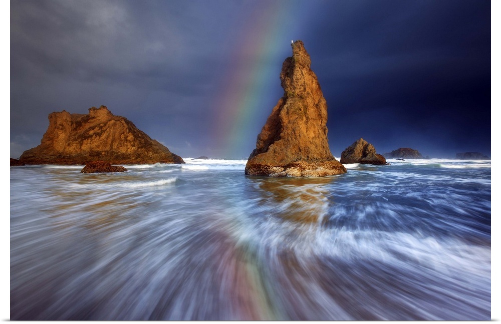 A rainbow over sea stacks in the ocean.